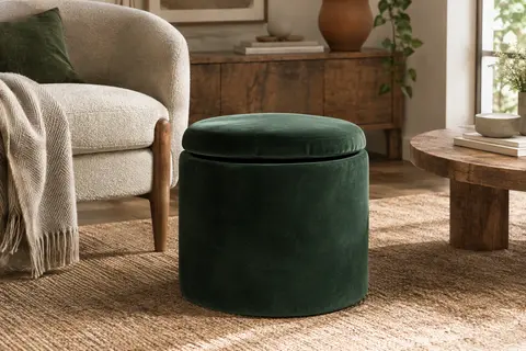 Pouf rond vert foncé à dessus rembourré, installé près d’un fauteuil dans un salon lumineux