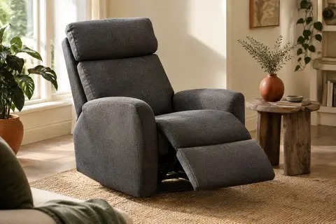 Fauteuil relax gris foncé en lin, incliné avec son repose-pieds déployé dans un salon lumineux.