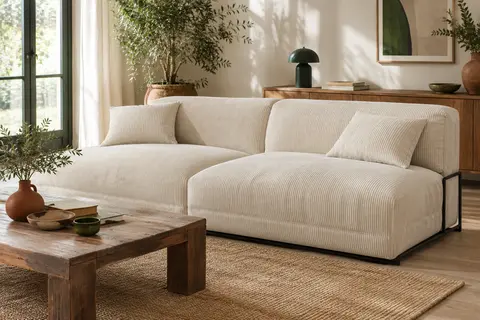 Canapé convertible trois places en velours côtelé ivoire présenté dans un salon lumineux au décor naturel.